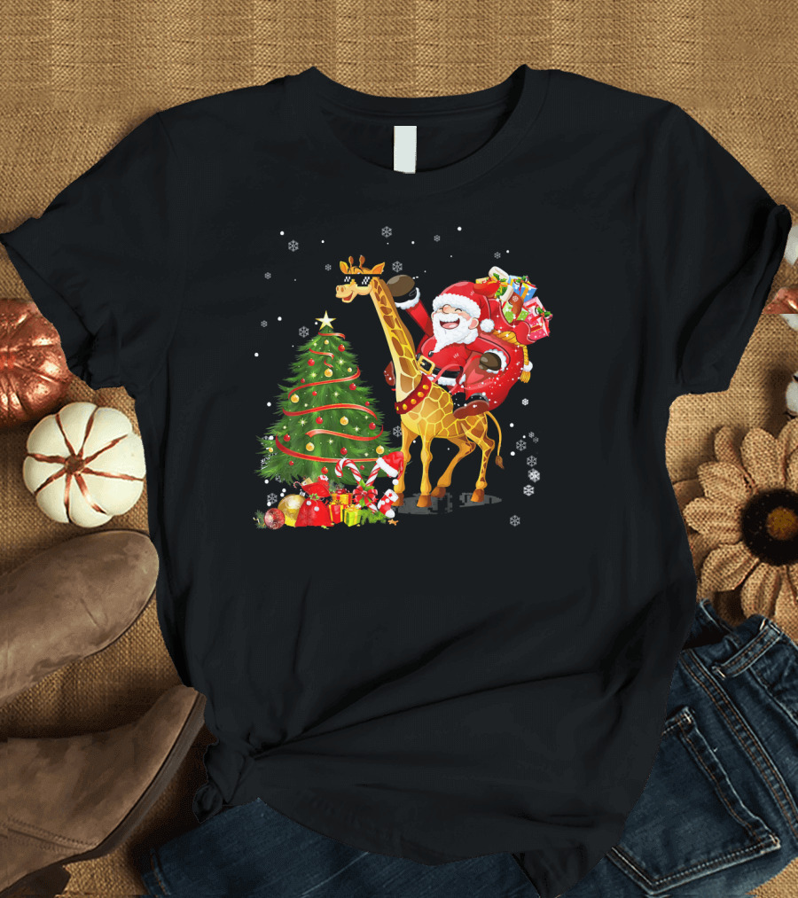Santa Claus Riding Giraffe with Gifts in Falling Snow Beside Decorated Christmas Tree T-Shirt