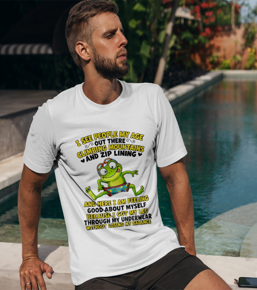 I See People My Age Climbing Mountains And Zip Lining Cartoon Frog Feeling Good Without Losing Balance T-Shirt