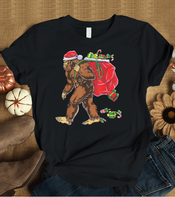 T-Shirt: Bigfoot Santa Hat Carrying Christmas Presents and Candy Canes T-Shirt Bigfoot Santa Hat Carrying Christmas Presents and Candy Canes T-Shirt